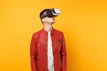 Portrait vogue cute young man in red leather jacket t-shirt looking up in headset standing isolated on bright trending yellow background. People sincere emotions lifestyle concept. Advertising area.