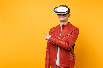 Portrait vogue handsome young man in red leather jacket, t-shirt looking in headset standing isolated on bright trending yellow background. People sincere emotions lifestyle concept. Advertising area.