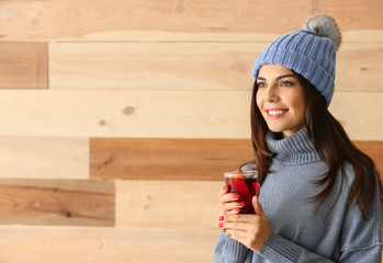 Woman with glass of delicious mulled wine on wooden background