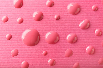 Drops of nail polish on pink paper, closeup