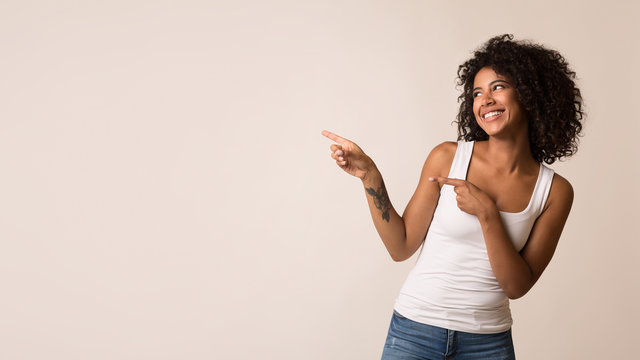 Happy african-american woman pointing away at copy space
