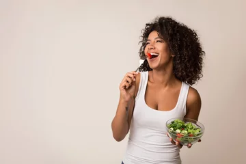 Fotobehang Excited lady eating healthy salad over light background © Prostock-studio
