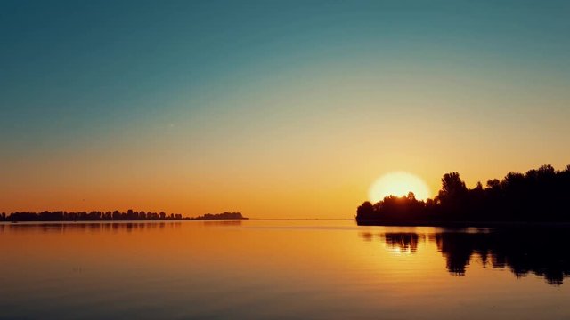 Amazing beautiful sunrise sky over calm smooth river surface. Summertime, dynamic scene, 4k video.