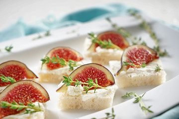 Tasty canapes with ripe fig and cream cheese on plate, closeup