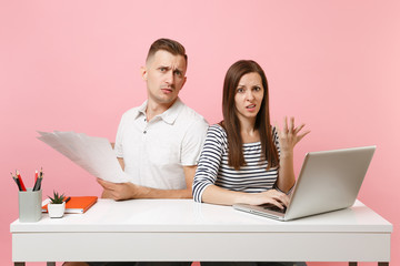 Two young angry business woman man colleagues sit work at white desk with contemporary laptop isolated on pastel pink background. Achievement career concept. Copy space advertising, youth co working.