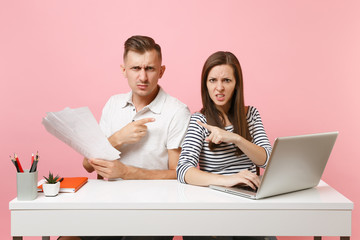 Two young angry business woman man colleagues sit work at white desk with contemporary laptop...