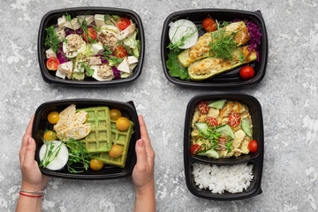Plastic containers with delicious food on gray background