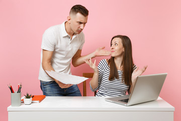 Two young angry business woman man colleagues sit work at white desk with contemporary laptop...