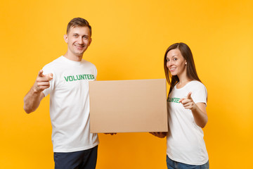 Colleagues couple in white t-shirt with written inscription green volunteer hold cardboard box...