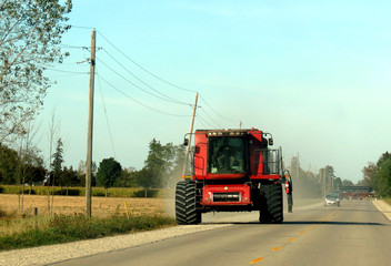 Naklejka premium A farmer driving a giant tractor along the highway.
