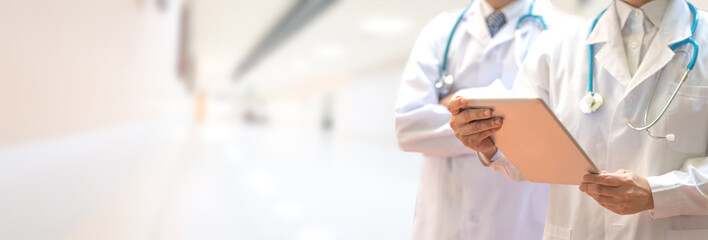 Medical healthcare doctor team concept. Physicians in white gown and stethoscope, hand holding computer tablet on blur background corridor hospital for copy space.