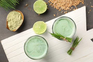 Glasses of wheat grass juice on grey table