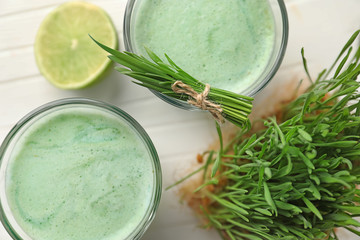 Glasses of wheat grass juice on white wooden table