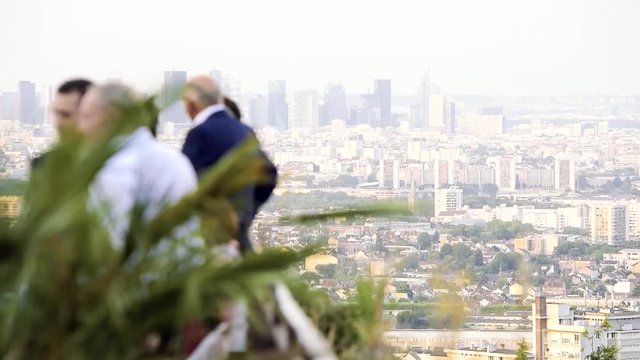 Business group of CEO, CFO, CTO team together discussing at outdoor meeting on a sunny day on terrace with Paris La Defense business district skyscrapers in the background