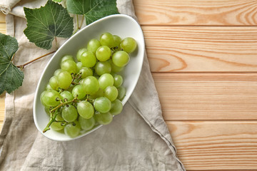 Plate with ripe sweet grapes on wooden table