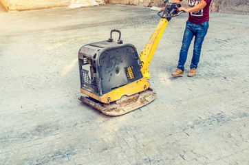 Reversible plate compacts pavement tiles laid on the street