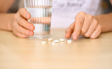 Woman with pills and glass of water at table