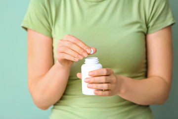 Woman holding jar with pills, closeup
