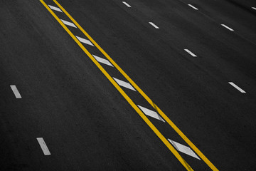 Yellow and white paint line on black asphalt. space transportation background