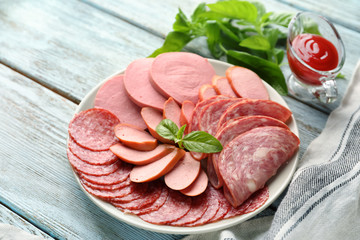 Plate with different kinds of sausages on wooden table