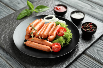 Delicious sausages with sauce and spices on slate plate