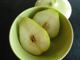 Fresh cut pear in retro modern bowl, spring green, white, yellow tones, black background