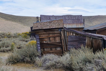 Derelict ghost town buildings in desert landscape evoke desolation on an overcast afternoon, Bodie, California USA.