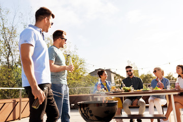 leisure and people concept - happy friends having barbecue party on rooftop