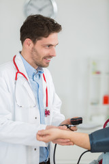 portrait of happy doctor checking patients blood pressure in clinic