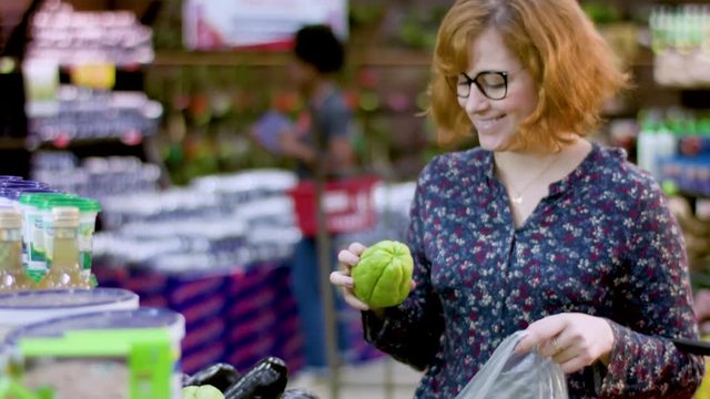 Beautiful and young redhead woman holding a fresh chayote or chuchu (Sechium edule)