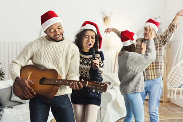 Happy friends singing together and playing on guitar