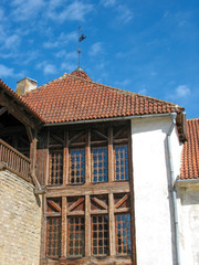 Europe. Part of the old medieval building: the roof covered by red shingles and wooden frame for windows, and white wall of the house. 
