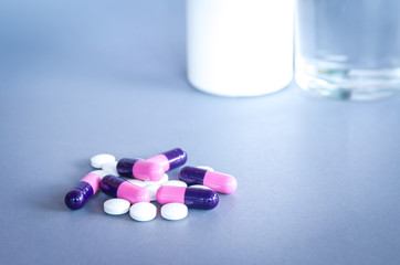 pills and tablets on grey background with bottle and glass