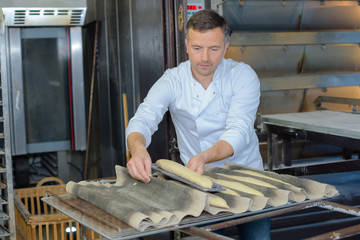 Baker putting baguettes on tray to cook