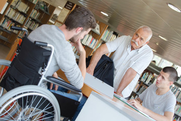 Fototapeta na wymiar student in wheelchair talking to teacher in the library