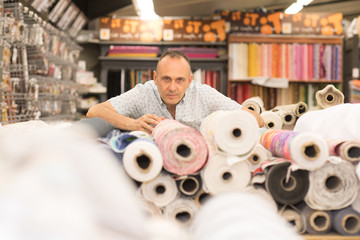 man using tablet selects fabric from storage shelves