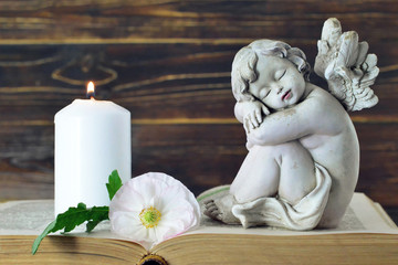Fototapeta na wymiar Memorial candle, angel figurine and flower
