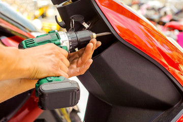 Master works as a screwdriver, repairs an electric scooter. close up