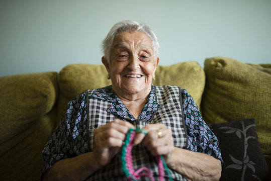 Portrait of smiling senior woman crocheting at home