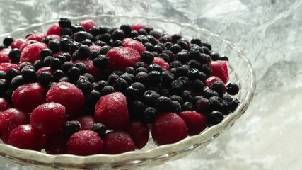 Frozen fruits of cherry and blueberries in a glass vase against a ice flowers on the window glass in the sun, background - Powered by Adobe