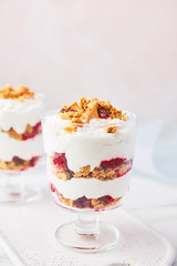 Close up of healthy raspberry yogurt parfait in a glass on white marble table over pink background with copy space.