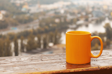 Orange cup of coffee on a background of nature