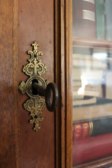 Old lock and key on antique bookshelf with glass doors