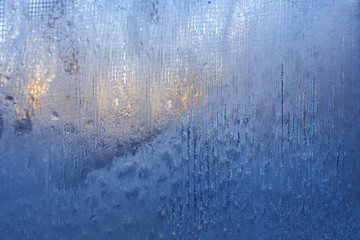Fototapeta na wymiar Blue frozen glass with striped frosty pattern and winter sun outside.