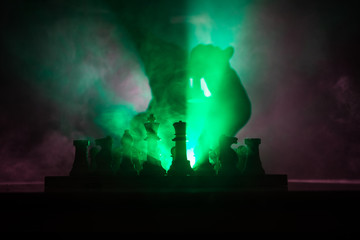 Man playing chess. Scary blurred silhouette of a person at the chessboard with chess figures. Dark toned foggy background.