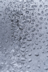 White frosty pattern formed from lot of frozen water drops on winter window.