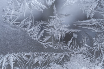 Winter frosty ice pattern with graceful pointed snowflakes on window.