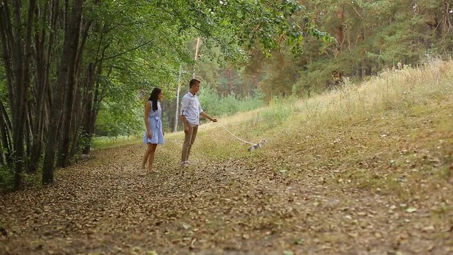 young couple walking in the woods on the track with his cat.