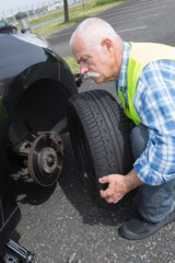 Fototapeta premium aged man changing leaking tire on the verge