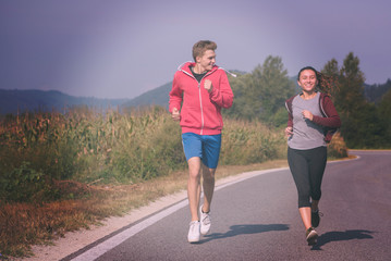 young couple jogging along a country road